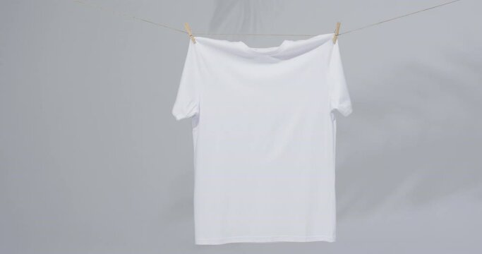 Video of white t shirt with clothes pegs and copy space on grey background