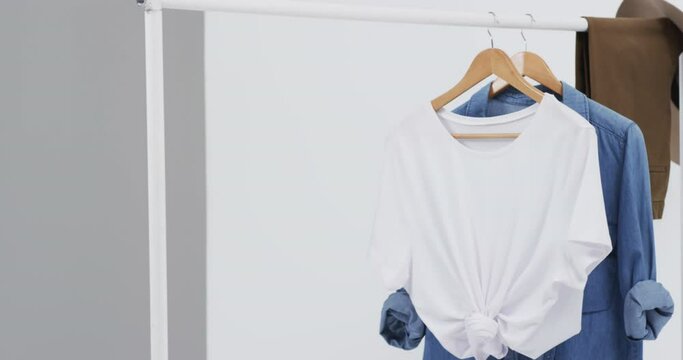 Video of white and denim t shirt on hangers, hat and copy space on white background