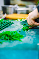 chef hands cuts green onions on board in kitchen