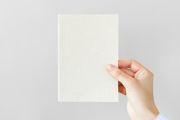 female hand holding a blank postcard on a gray background
