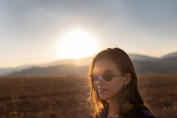 portrait of a beautiful young girl in glasses on a walk in the mountains. travel in the mountains at sunset.