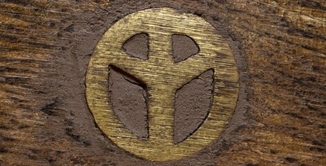 hippy peace symbol in gold metal on dark wood, copy space