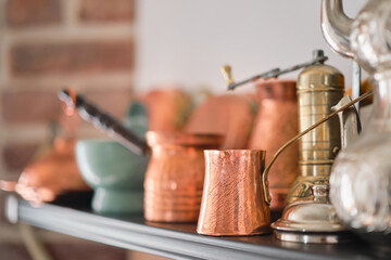 Handmade copper cezve, Turkish traditional tableware on a shelf in the kitchen at home or in a restaurant, selective focus