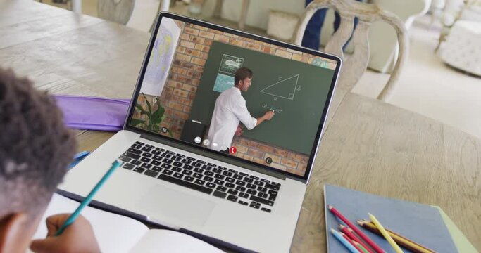 Diverse male student having class during laptop video call with male teacher in slow motion