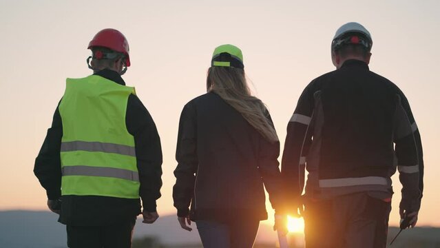 Unrecognizable coal mine workers in an open pit at sunset, slow motion