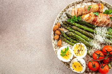 Baked chicken breast wrapped in bacon with asparagus, eggs and cherry tomato, Healthy fats, clean eating for weight loss. Keto paleo diet menu, top view