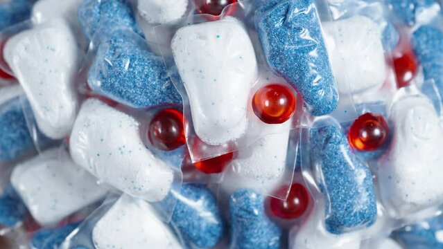 Soluble packets, dishwasher capsules, rotating from a top view.