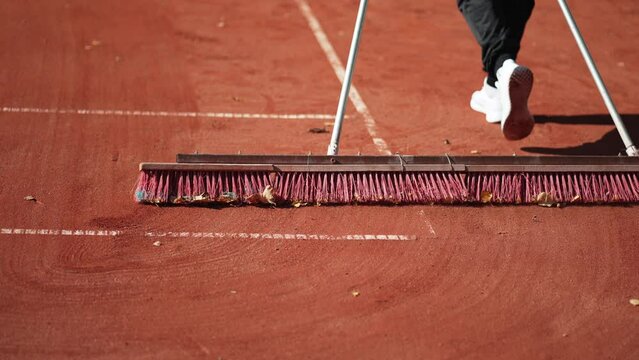 Using a coat brush for ground maintenance. Tennis court leveling and cleaning, slow motion