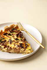 Portion of pie on a plate, homemade quiche with seasonal forest mushrooms Chanterelles on a yellow background