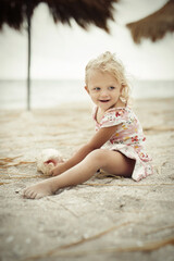 Two and half years old girl posing on sea beach with giant shell