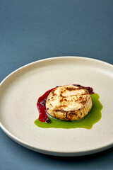 Baked Camembert cheese is taken with a fork and knife on a gray background