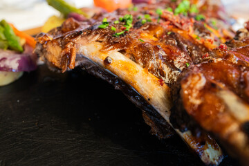 Roasted pork ribs at restaurant against black background with copy space, studio shot, close-up