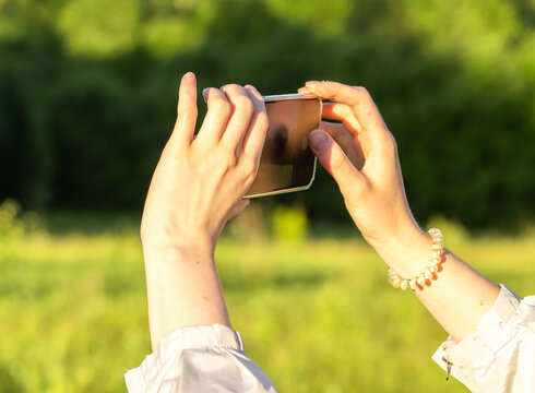 Hands holding mobile phone, taking photo, recording video in nature