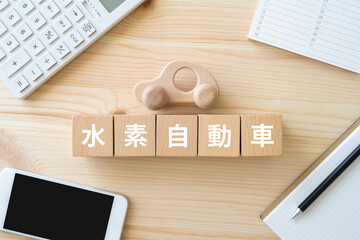 水素自動車と書かれたブロック、車のおもちゃ、電卓、スマホ