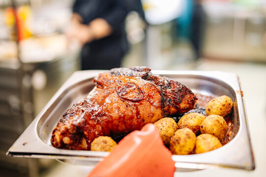 chef hand cooking Baked Pork knuckle with vegetables