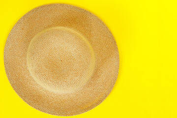Fashionable straw hat on yellow paper background.
