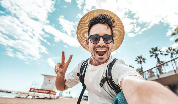 Happy young man taking selfie pic with smart mobile phone device outside - Smiling male tourist laughing at camera on summertime vacation - Summer holidays and modern technology life style concept