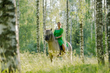Barefoot woman rider on Icelandic horse in sunny Finnish brirch  forest during sunset. Fairytale like feeling.