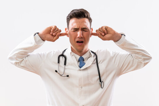 Image of overworked doctor with hands in ears .	