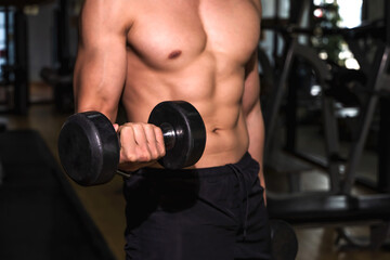 Fototapeta na wymiar Close up strong six packs fitness man holding dumbbell in gym, Fitness in the gym