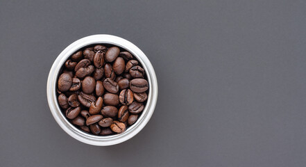 Coffee beans in a cup on gray background 