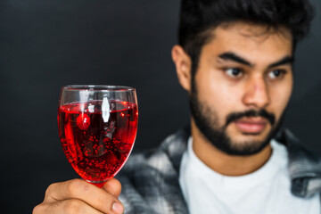 The image exhibits a man in a passive pose, holding a red colored drink, ideal for promotional...
