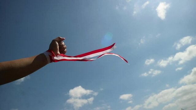 Hand wearing red and white ribbon, Indonesian independence day concept