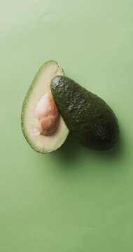 Vertical video of sliced avocado with copy space over green background