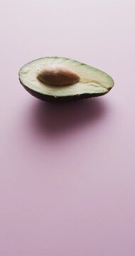Vertical video of sliced avocado with copy space over pink background