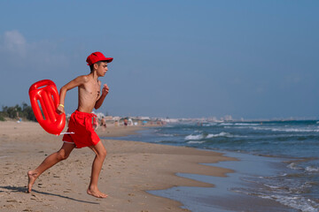 Lifeguard boy with lifeguard float running on the beach