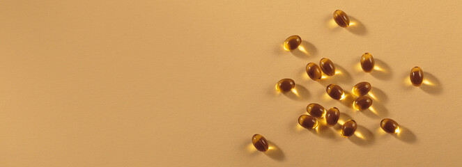 Diet, nutrition, healthy eating concept. Little oil filled yellow softgels capsules of food supplements on beige background.
