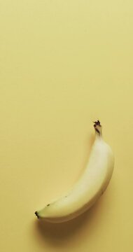 Vertical video of banana with copy space over yellow background