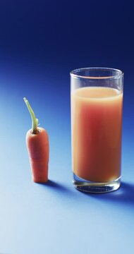 Vertical video of carrot and carrot juice with copy space on blue background