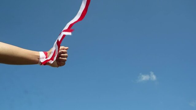Hand wearing red and white ribbon, Indonesian independence day concept