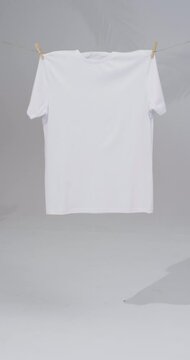 Vertical video of white t shirt with clothes pegs and copy space on white background
