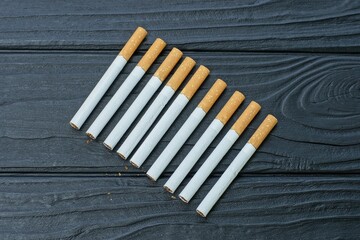 a lot of white with a yellow filter harmful to health with tobacco modern new cigarettes for smoking lie on a black wooden table