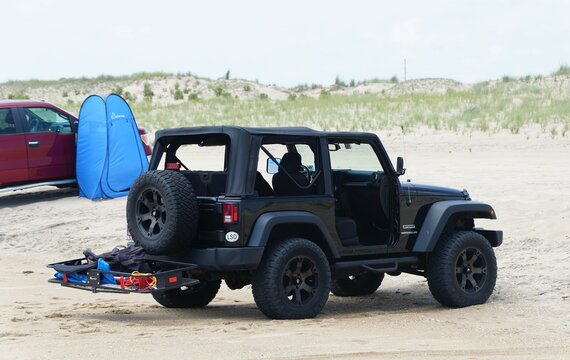 Fenwick Island, Delaware, U.S - July 8, 2023 - A black Jeep Wrangler with surf fishing beach permit parked on the sand