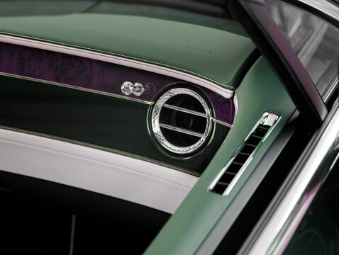 ventilation nozzles in luxury car interior with ambient lighting and green leather