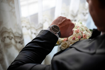 Close up of businessman looking at watch on his hand outdoors, free space. Man in white shirt...