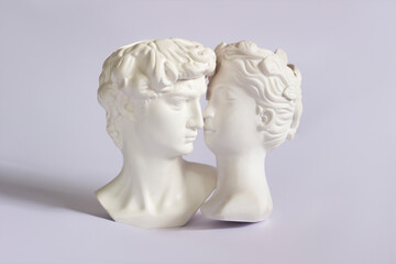Two antique statue's heads isolated on a white background. Relationships of man and woman. Love, romance, kiss, tenderness. Modern design. Contemporary art. David and Aphrodite