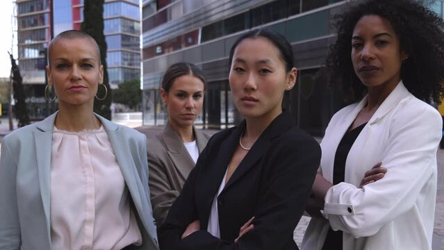 Four multiracial empowered women looking at camera confident and with serious face at the office district.