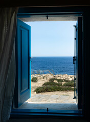 The view at the sea from an open traditional blue window with blue shutters , Ayia Napa, Cyprus