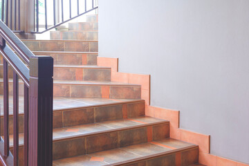 Brown tile steps of interior spiral staircase with wooden handrail inside of vintage house