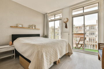 a bedroom with a bed, desk and window overlooking out onto the canal in amsterdam photo viatafo com