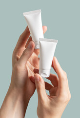 Hand holding two small cream tubes mock-ups