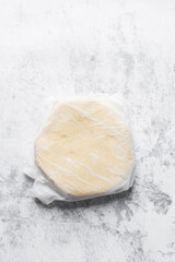 Top view of sugar cookie dough wrapped in parchment paper, process of making sugar cookies