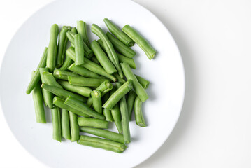 Fresh chopped green beans in a round plate, on a white background. top view 