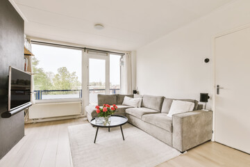a living room with a couch, coffee table, tv and large window looking out onto the street in london