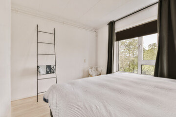 a bedroom with white walls and black curtains on the window sing it's large bed in the room