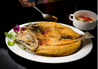 Thai style deep fried sea bass fish with sweet fish sauce served with mango salad